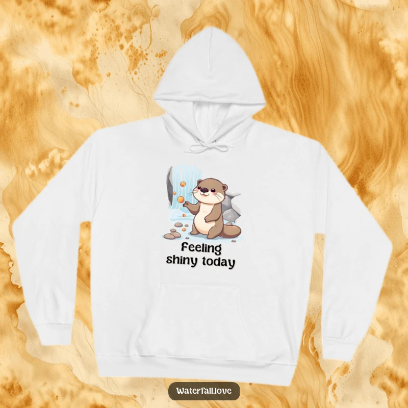 Funny otter juggling shiny pebbles by a cascading waterfall, printed on a warm and humorous hoodie.